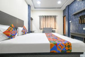 a hotel room with a bed and a chair at FabHotel Shree Khatu Shyam Palace in Indore