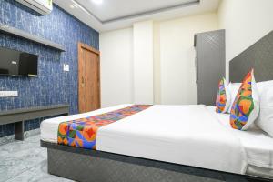 1 dormitorio con 1 cama y TV en la pared en FabHotel Shree Khatu Shyam Palace, en Indore