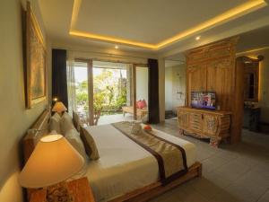a bedroom with a large bed and a television at The Nenggala Suite in Tegalalang