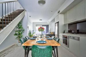 a kitchen with a wooden table with green chairs at Superb 3 Bedroom Apartment Surry Hills in Sydney