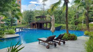 una piscina con 2 sillas y una sombrilla en Bright Apartment Close to Amazing Beach ! 39 Sqm en Nai Yang Beach