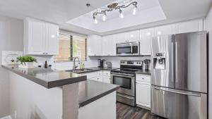 a kitchen with white cabinets and a stainless steel refrigerator at Beautiful newly remodeled 2-Bdrm Biltmore Condo in Phoenix