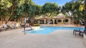 a swimming pool with chairs and a house at Beautiful newly remodeled 2-Bdrm Biltmore Condo in Phoenix