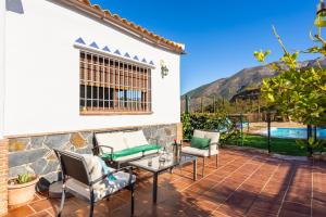 patio con sedie, tavolo e piscina di Casa La Vina De La Tireta a Viñuela