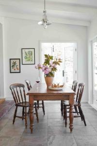 una mesa de comedor con sillas y un jarrón con flores. en Little Oak Cygnet, en Cygnet