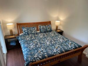 a bed with a blue comforter and two lamps at Bellingen Treehouse in Bellingen