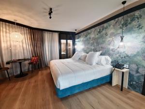 - une chambre avec un grand lit blanc orné d'une peinture murale dans l'établissement Hotel Suites Moma Centro, à Villanueva de la Serena