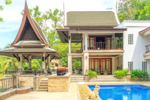 a villa with a swimming pool and a house at Classic Thai style Cozy Villa pool garden in Patong Beach