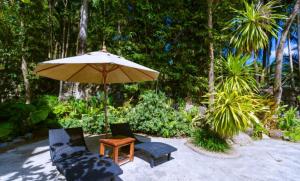 a patio with two chairs and a table and an umbrella at Classic Thai style Cozy Villa pool garden in Patong Beach