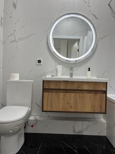 a white bathroom with a toilet and a mirror at Raisson Ahotel GT32 in Astana