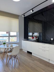 a kitchen with white cabinets and a table and a black wall at Raisson Ahotel GT32 in Astana