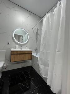 a white bathroom with a sink and a mirror at Raisson Ahotel GT32 in Astana