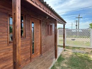 un porche de madera de una casa con una valla en Chalés confortáveis, en Río Grande