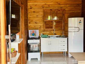 a kitchen with a white refrigerator and a stove at Chalés confortáveis in Rio Grande