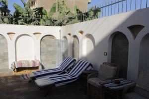 two chairs and chairs on a patio with arches at Nour House in Luxor