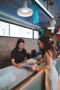 two women standing at a counter in a restaurant at ISTY Hotel -SHA Extra Plus in Chiang Mai