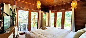 een slaapkamer met een bed, een tv en ramen bij Uma Villa Manado in Manado