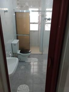 een witte badkamer met een toilet en een wastafel bij Apartamento Pé Na Areia in Mongaguá +17 foto's