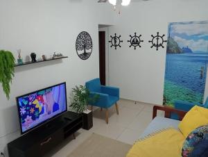 een woonkamer met een flatscreen-tv en blauwe stoelen bij Apartamento Pé Na Areia in Mongaguá
