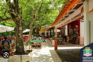 een gebouw met een boom en tafels en stoelen bij Apartamento Pé Na Areia in Mongaguá