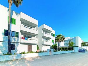 a white building with a car parked in front of it at Apartamentos Sivella in Port de Pollensa