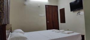 um quarto com uma cama e uma televisão na parede em Beun Residency em Nagercoil