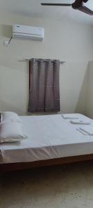 uma cama com lençóis brancos e almofadas num quarto em Beun Residency em Nagercoil