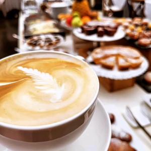 una tazza di caffè seduta su un tavolo con pasticcini di Cortona Resort & Spa a Cortona