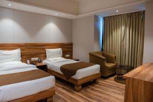 a hotel room with two beds and a chair at Hotel The Shiv Regency in Gandhidham