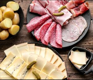 uma mesa com diferentes tipos de carnes e queijos em Chalet en A de la Motte-Fanjas 