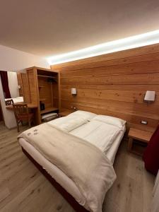 a bedroom with a large bed with a wooden wall at Albergo Garni Martina in Carisolo