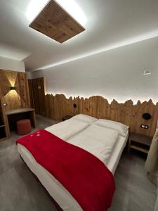 sypialnia z dużym łóżkiem i drewnianą ścianą w obiekcie Albergo Garni Martina w mieście Carisolo