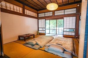 a bedroom with a bed in a room with windows at 恐竜博物館より車で15分 -1組様限定の築140年の古民家農家民宿 "晴れのちもっと晴れ" 里山集落で超田舎滞在- 昔懐かしい五右衛門風呂とにわとり卵の収穫体験付き 