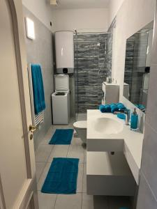 een badkamer met een wastafel, een toilet en blauwe tapijten bij Menton centre Vue imprenable sur mer et jardin Biovès in Menton