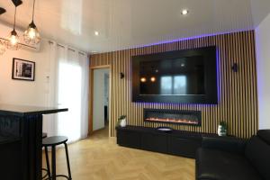 sala de estar con chimenea y TV en la pared en Appartement de luxe avec sauna pour 4 Personnes, en Triel-sur-Seine
