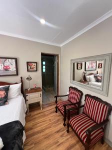a bedroom with two chairs and a bed and a mirror at Zwartmodder Clarens in Clarens