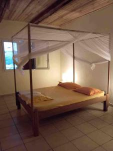 Bett mit Baldachin in einem Zimmer in der Unterkunft VILLA RAVOLA - Ambondrona in Nosy Be
