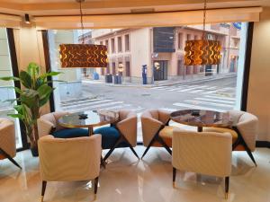 un restaurant avec deux tables et des chaises devant une fenêtre dans l'établissement Hotel Suites Moma Centro, à Villanueva de la Serena