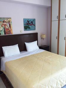una camera con un grande letto con testiera in legno di Angelica Villas Hotel Apartments ad Antica Epidauro
