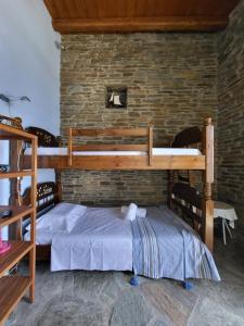 a bedroom with two bunk beds and a brick wall at The Stone Lookout Villa in Apróvaton