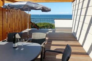 tavolo e sedie con ombrellone e oceano di Aparthotel Waterkant Suites - Fewos am Meer mit SPA a Börgerende-Rethwisch