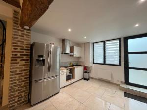 a large kitchen with a stainless steel refrigerator at Duplex belle pierre in Digoin