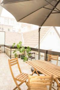 a wooden table and chairs under an umbrella on a balcony at The Gallery Apartment in Novi Sad