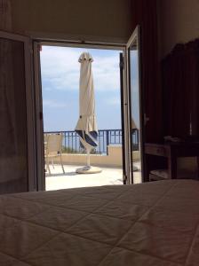 a room with a bed and an open door with a umbrella at Angelica Villas Hotel Apartments in Ancient Epidauros
