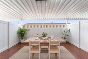 a white dining room with a table and chairs at The Elements l Fire l 4 Stunning Apartments each with Private Outdoor Dining l Walk to the Beach l Family Friendly l Wifi l Netflix l Outdoor Shower l Communal BBQ Pavilion and Lawn Area l in Christies Beach