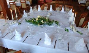 Una larga mesa blanca con vasos y flores. en Weißer Stein Jonsdorf, en Kurort Jonsdorf