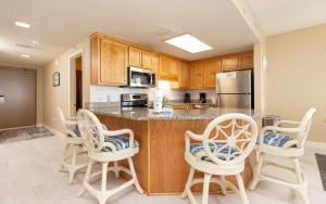 a kitchen with wooden cabinets and a counter with chairs at Phoenix X 317 in Orange Beach