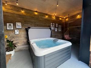 a hot tub in a room with a wooden wall at Beautiful country barn with hot tub and amazing views in Princes Risborough