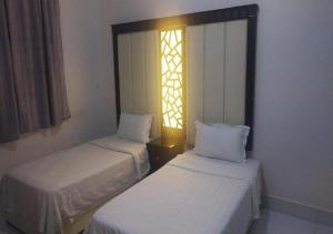 two beds in a room with a window at نجمة الحسناء in Jeddah
