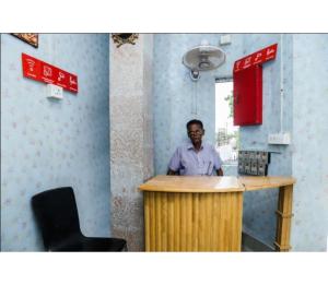 Un uomo in piedi al bancone in una stanza di Hotel Residency, Tripura a Rādhākishorepur